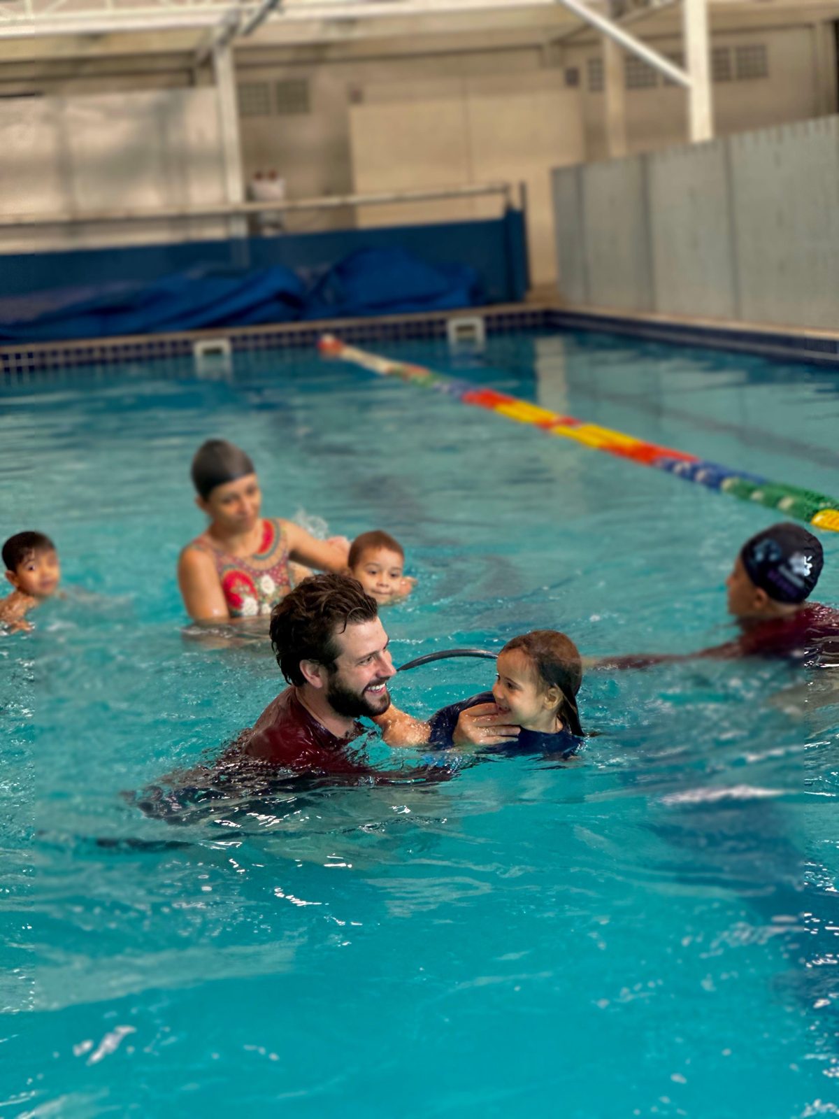 Professor sorrindo com criança na piscina da Acquademy